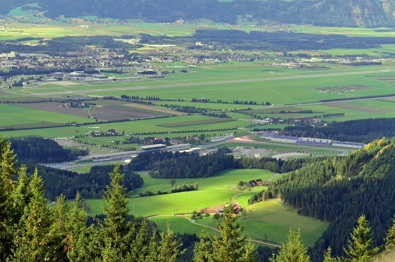 Blick auf die grüne Hügellandschaft rund um Spielberg und den Red Bull Ring an einem sonnigen Tag